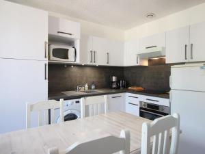 - une cuisine avec des placards blancs, une table et des chaises dans l'établissement Appartement Mont-Dore, 3 pièces, 5 personnes - FR-1-608-255, à Le Mont-Dore