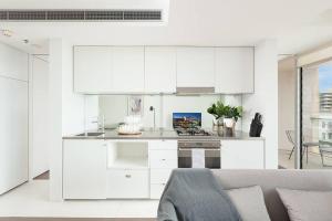 a white kitchen with white cabinets and a couch at DH707 - 1 bedroom unit Victoria St - Darlinghurst in Sydney