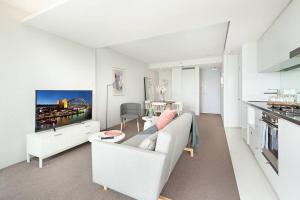 a white living room with a couch and a tv at DH707 - 1 bedroom unit Victoria St - Darlinghurst in Sydney