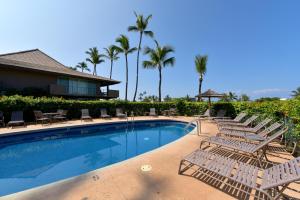 a resort swimming pool with lounge chairs and palm trees at Eldorado D106 in Kahana