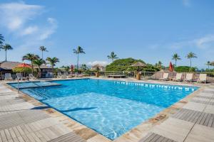 a pool at a resort with chairs and palm trees at Eldorado D106 in Kahana