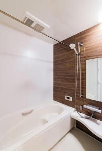 a white bath tub in a bathroom with a mirror at Chalet Setsugekka in Hakuba