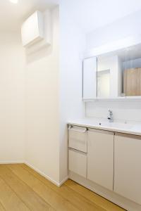 a white kitchen with a sink and a mirror at Shinjuku City House 新宿シティハウス in Tokyo