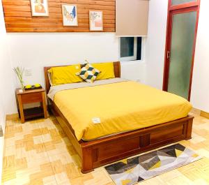 a bedroom with a bed with yellow sheets and a table at GERBERA HOTEL in Quy Nhon