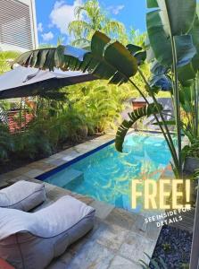 Stuart Park的住宿－Lush Tropical Paradise Home - Darwin City，一个带枕头和遮阳伞的小型游泳池