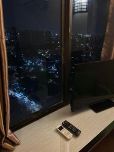 een televisie en twee afstandsbedieningen naast een raam bij Highlander Apartemen Rajawali in Jakarta