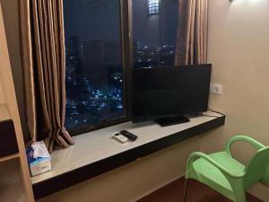 a room with a window with a television and a chair at Highlander Apartemen Rajawali in Jakarta