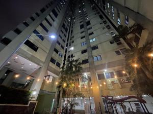 a tall building with palm trees in front of it at Highlander Apartemen Rajawali in Jakarta