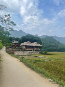 un chemin de terre à côté d'un bâtiment avec des montagnes en arrière-plan dans l'établissement Mai Chau Hillside Homestay, à Mai Châu