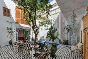 un patio con sillas, mesa y árboles en Riad Botanica, en Marrakech