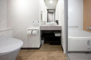 a bathroom with a sink and a toilet and a tub at Shizutetsu Hotel Prezio Osaka Shinsaibashi in Osaka