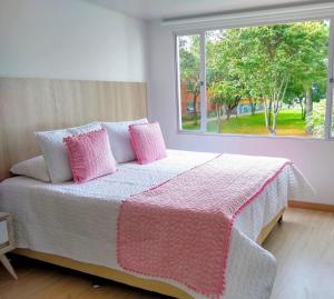een slaapkamer met een bed met roze kussens en een raam bij FEDERMAN PARK HOTEl in Bogota