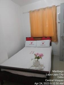 a bedroom with a bed with a vase with flowers on it at WJV INN MARIBAG0 in Maribago