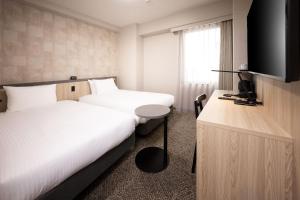 a hotel room with two beds and a flat screen tv at Shizutetsu Hotel Prezio Osaka Shinsaibashi in Osaka