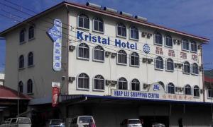 Un edificio con un hospital acritiológico con coches aparcados delante. en Hotel Kristal, Keningau, en Keningau