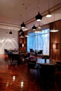 un restaurante con mesas, sillas y luces colgantes en Marriott Executive Apartment Tianjin Lakeview, en Tianjin