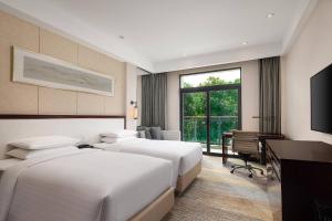 無錫市にあるCourtyard by Marriott Wuxi Lihu Lakeのベッド2台とデスクが備わるホテルルームです。