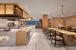 cocina abierta y comedor con mesas y sillas en Courtyard by Marriott Wuxi Lihu Lake en Wuxi