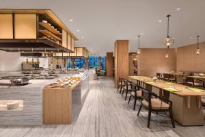 an open kitchen and dining room with tables and chairs at Courtyard by Marriott Wuxi Lihu Lake in Wuxi
