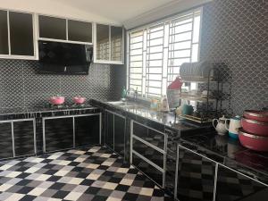 a kitchen with black counters and a checkered floor at Marimar Stayz Tandop in Alor Setar