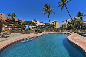 a swimming pool in a resort with palm trees at Kahana Villa E601 in Kahana