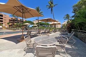 a table and chairs with umbrellas next to a pool at Kahana Villa E601 in Kahana