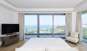 a bedroom with a large bed and a television at The Westin Blue Bay Resort & Spa in Lingshui