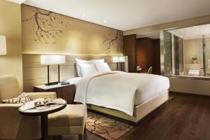 a bedroom with a large bed and a living room at Marriott Executive Apartments Tianjin TEDA in Binhai