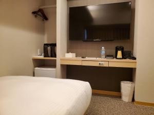 a bedroom with a bed and a desk with a television at Trust Hotel in Hiroshima