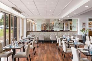 une salle à manger avec des tables et des chaises blanches dans l'établissement Renaissance London Heathrow Hotel, à Hillingdon