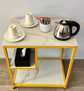 a yellow table with a tea pot and dishes on it at Sydney RiseOn Hotel in Sydney