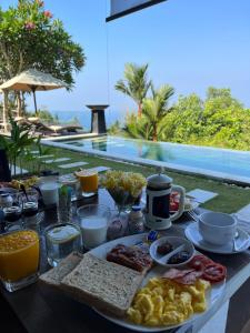 a breakfast table with breakfast foods on a table in front of a pool at The Puncak Lombok in Senggigi 