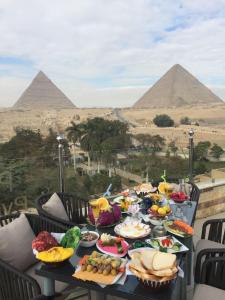 una tavola piena di cibo con le piramidi sullo sfondo di Sky Pyramids View Inn a Il Cairo