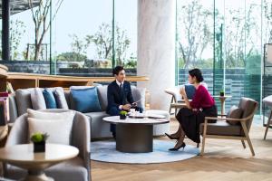 Ein Mann und eine Frau, die in einer Lobby am Tisch sitzen. in der Unterkunft Suzhou Marriott Hotel Taihu Lake in Suzhou