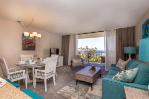 a living room with a blue couch and a table and chairs at Kaanapali Shores 527 in Kahana