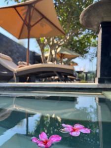 a pool with a table and an umbrella and flowers at The Puncak Lombok in Senggigi