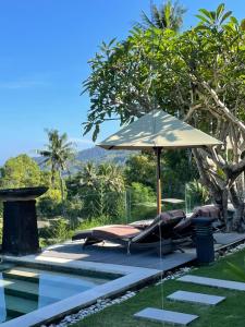 a pool with an umbrella and chairs next to a swimming pool at The Puncak Lombok in Senggigi 