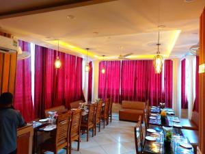 a dining room with red curtains and tables and chairs at Hotel sunshine & restaurant in Pūrnia +25 photos