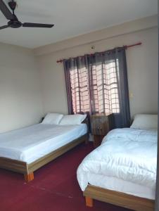 duas camas num quarto com duas janelas em Namaste Stay Apartment em Pokhara