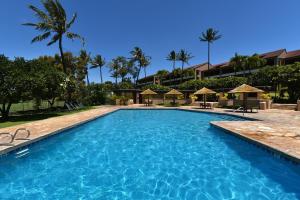 una piscina en un complejo con palmeras y sombrillas en Kaanapali Royal D302 en Lahaina