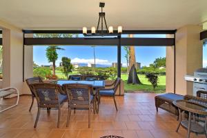 a dining room with a table and chairs and a large window at Kaanapali Royal N102 in Lahaina