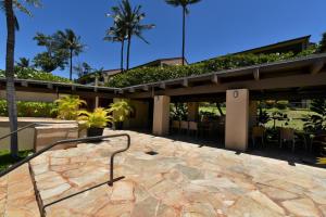 un edificio con un patio con sillas y palmeras en Kaanapali Royal D302 en Lahaina