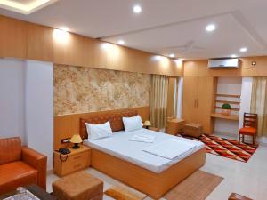 a bedroom with a bed and a chair and a couch at Hotel sunshine & restaurant in Pūrnia