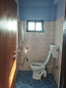 uma casa de banho com WC e uma janela na parede em Namaste Stay Apartment em Pokhara