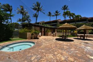 um pátio com piscina e guarda-sol e um edifício em Kaanapali Royal C202 em Lahaina