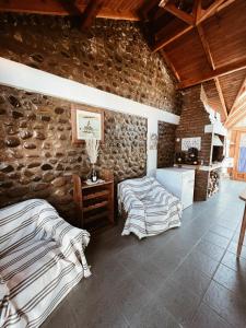 a bedroom with two beds and a stone wall at Casa Arrayanes Tempo in Esquel