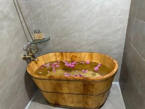 El baño incluye una bañera de madera llena de flores. en Bac Ha Lodge Retreat en Bắc Hà