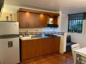 a kitchen with wooden cabinets and a white refrigerator at Acogedor Apartamento Urbanización Tricentenario in Medellín