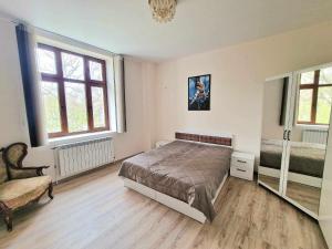 a bedroom with a bed and a chair and windows at Апартаменти Москва in Dobrich