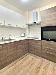 eine Küche mit Holzschränken, einer Spüle und einer Mikrowelle in der Unterkunft Апартаменти Москва in Dobritsch